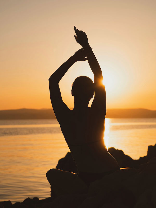 Woman practicing yoga at sunset, representing DUTCH Plus hormone and stress test to support balanced health and wellbeing.